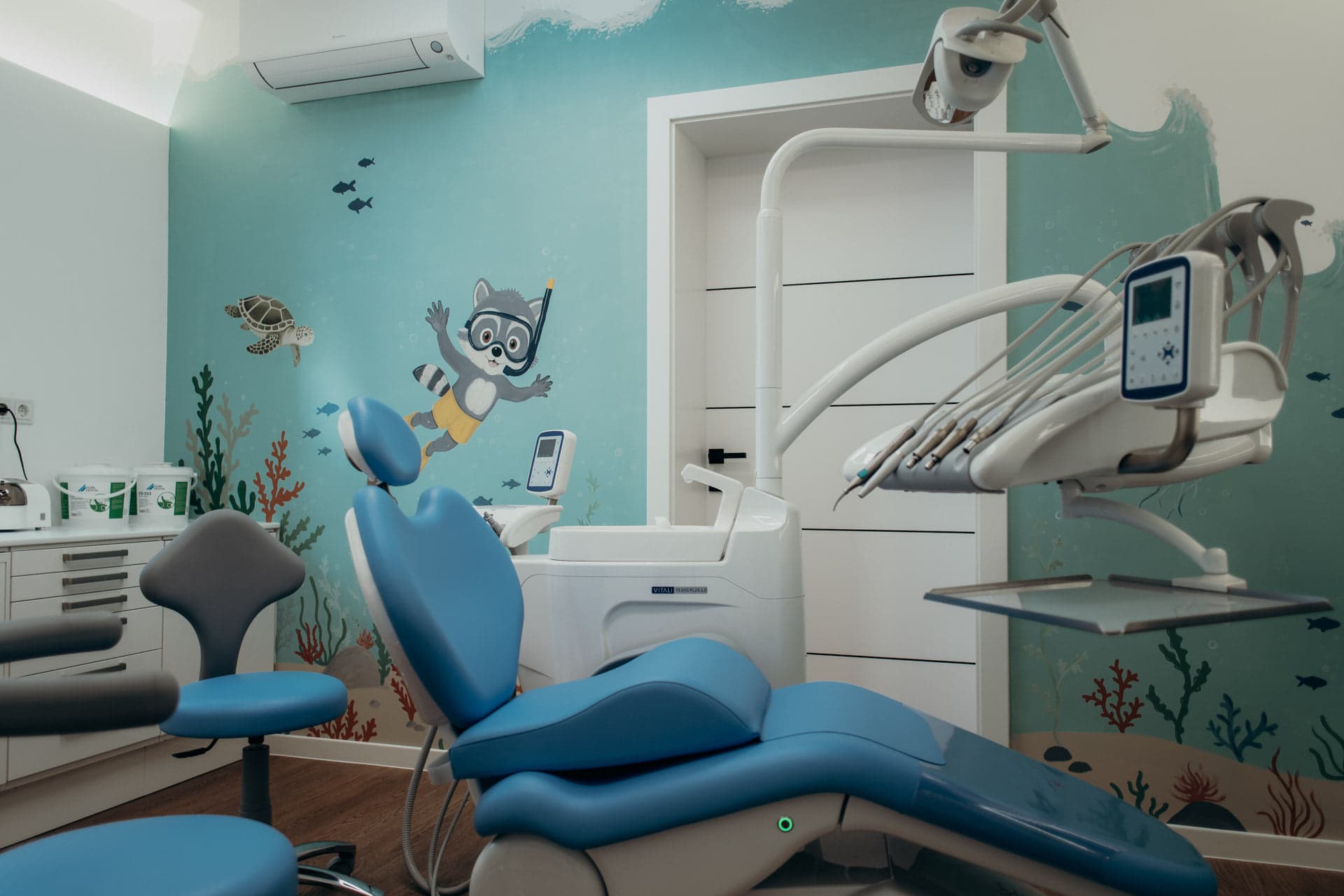 Zwei Kinder im Behandlungszimmer bei kidsReinisch, eines zeichnet, eines steht am Fenster